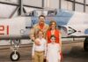 a family poses in front of an airplane