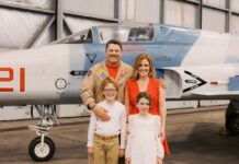 a family poses in front of an airplane