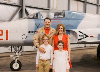 a family poses in front of an airplane