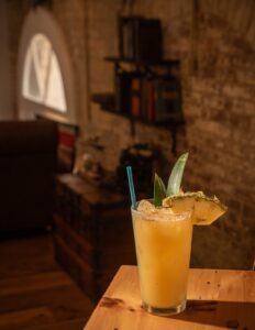 a glass of orange juice sitting on top of a wooden table