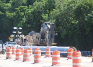 a large truck driving down a road surrounded by traffic cones