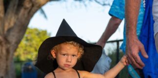 a little girl in a witches costume walking down the street