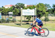 a man riding a bike down a street next to a sign