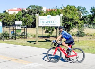a man riding a bike down a street next to a sign