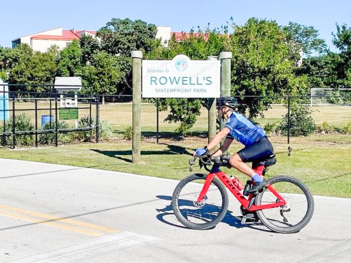 a man riding a bike down a street next to a sign