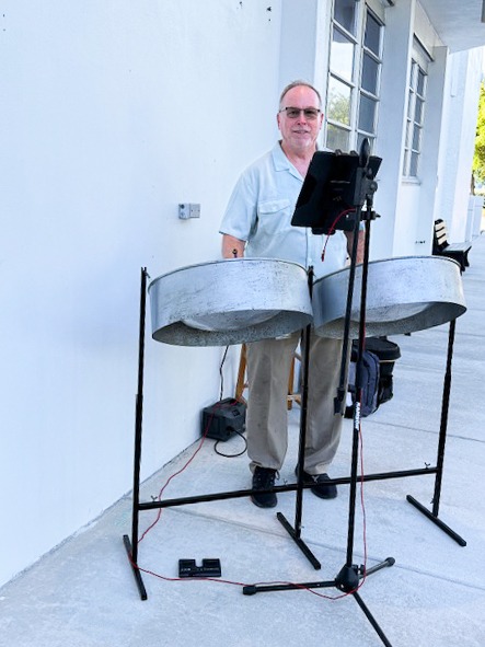a man standing next to a pair of steel pans