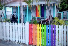 a rainbow colored house with a white picket fence