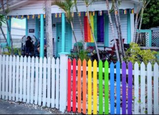a rainbow colored house with a white picket fence