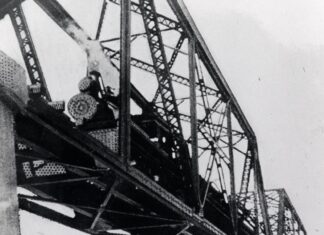 a black and white photo of a train bridge