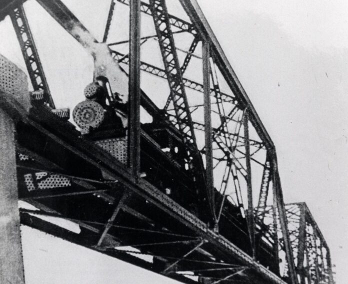 a black and white photo of a train bridge