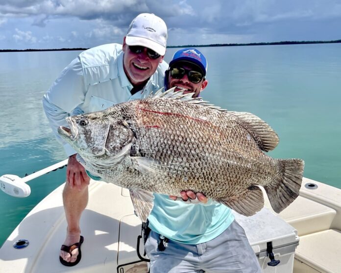 a man and a boy on a boat holding a fish