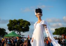 IN PICTURES: SPOOKY CREATURES, SUPERHEROES AND MORE TAKE TO FOUNDERS PARK FOR TRUNK-OF-TREAT a woman in a white dress is walking in a crowd