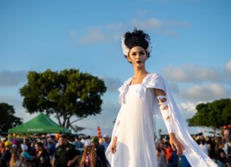 a woman in a white dress is walking in a crowd