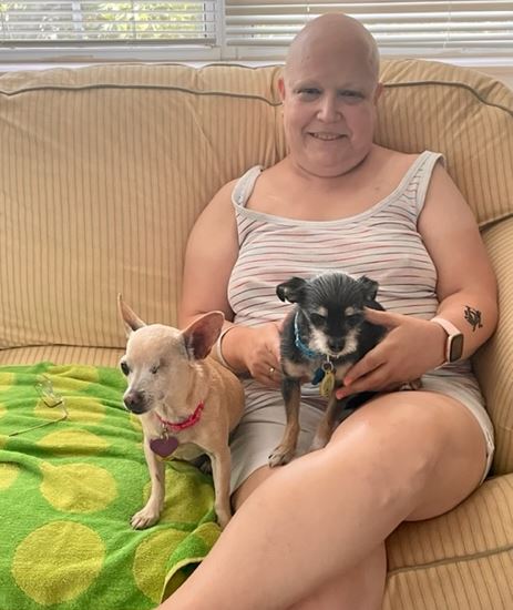 a woman sitting on a couch with two dogs
