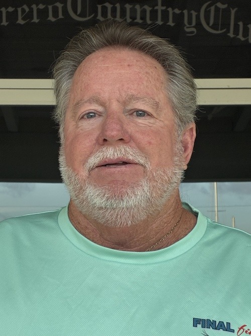 a man in a green shirt standing in front of a sign