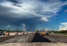a road under a cloudy sky with construction equipment
