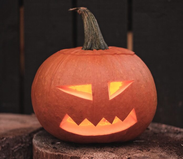 a carved pumpkin sitting on top of a tree stump