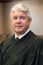 a man in a black robe standing in a room