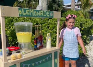 9-YEAR-OLD JADEYN HOLMES’ LEMONADE STAND SERVES CHARITY BY THE CUP a little girl standing in front of a lemonade stand