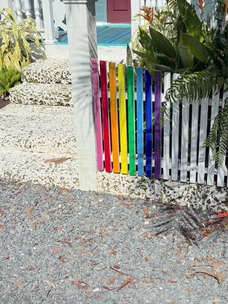 a rainbow colored fence in front of a house