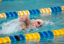CORAL SHORES’ LYKINS & SMITH PUNCH TICKETS TO STATES IN THE POOL a man swimming in a pool with a yellow hat