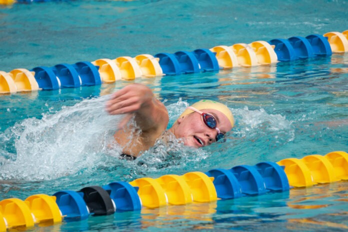 9 a man swimming in a pool with a yellow hat