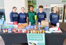 a group of people standing behind a table full of food