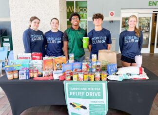 CORAL SHORES INTERACT RAISES FUNDS FOR HURRICANE MELISSA RELIEF a group of people standing behind a table full of food