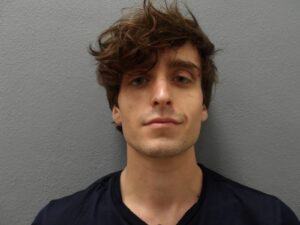 a man with long hair standing in front of a wall