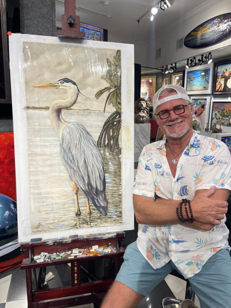 a man sitting in front of a painting of a bird