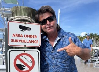 a man giving a thumbs up next to a sign