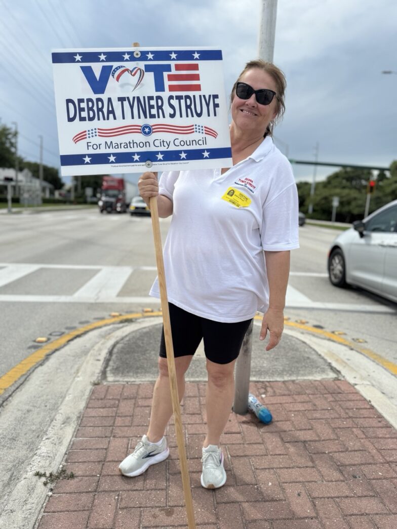 a woman holding a sign on the side of the road