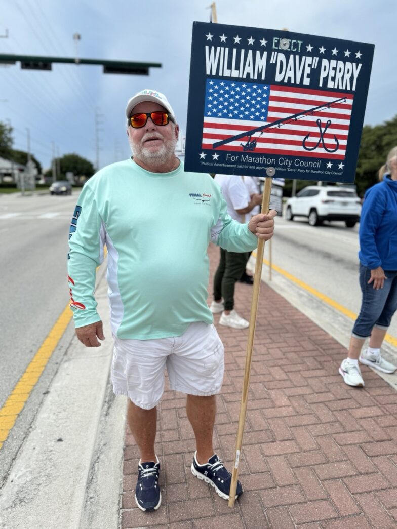 a man holding a sign on the side of the road