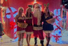 IN PICTURES: LIGHTHOUSE GLOWS OVER LOCAL VENDORS AT FARO BLANCO a group of people dressed as santa clause posing for a photo