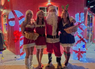 IN PICTURES: LIGHTHOUSE GLOWS OVER LOCAL VENDORS AT FARO BLANCO a group of people dressed as santa clause posing for a photo