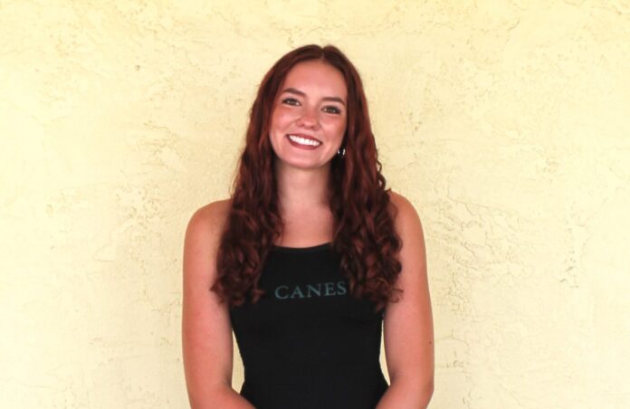 a woman standing in front of a yellow wall