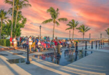 a crowd of people standing around a pool at sunset