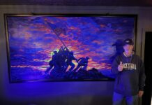 RENOWNED ARTIST UNVEILS ‘RAISING THE FLAG’ AT THE ARMORY SPEAKEASY IN KEY LARGO a man standing in front of a painting