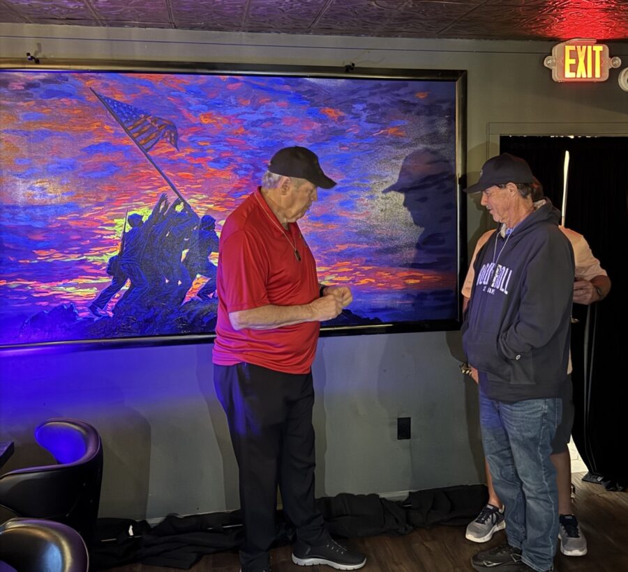 two men standing in front of a large painting