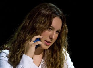 a woman in a white shirt talking on a cell phone