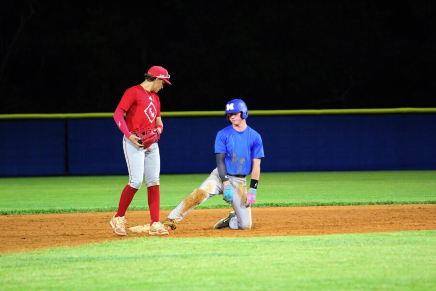 a baseball player standing next to another player on a field
