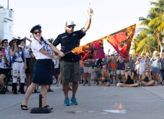 HURRICANE SEASON IS ON HIATUS: KEY WEST BURNS WARNING FLAGS IN ANNUAL CEREMONY a man standing next to a woman on top of a street