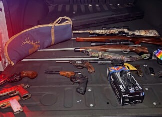 the back of a car with a bunch of guns in the trunk