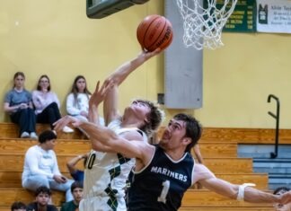 HOOPS ACTION HEATS UP AS TEAMS REACH HALFWAY POINT OF REGULAR SEASON a group of young men playing a game of basketball