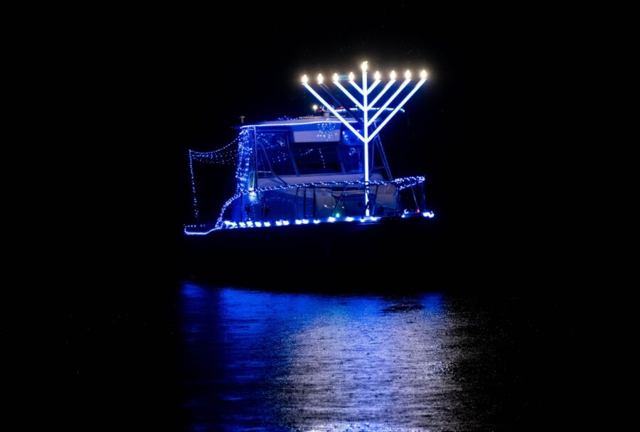 a boat with a lit up menorah on it in the water