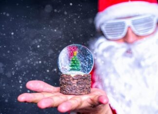 Festive image of a Santa figure holding a snow globe with a Christmas tree.
