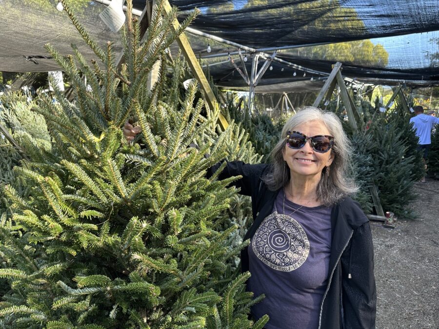 a woman standing next to a christmas tree