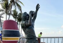 a statue of a man reaching up to catch a frisbee