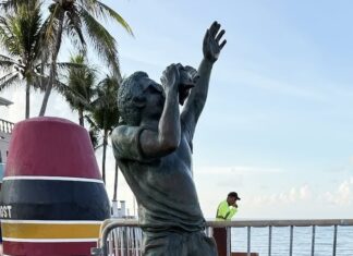 a statue of a man reaching up to catch a frisbee