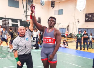 WRESTLERS HIT THE MATS & BRING HOME TOURNAMENT WINS a man standing on a basketball court holding a basketball
